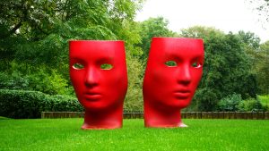 Large red mask sculptures on green grass